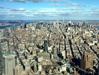 Aerial view of modern buildings in city against sky on sunny day