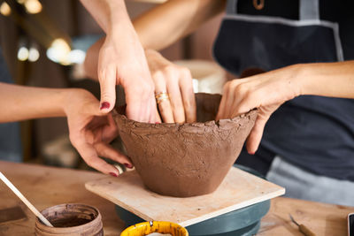 Cropped hands of potters making earthenware at pottery workshop