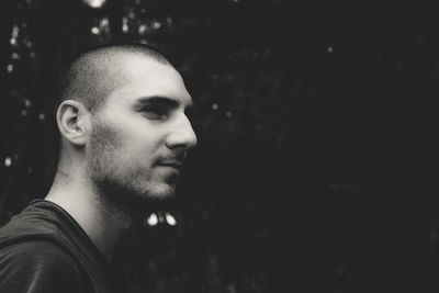 Close-up of thoughtful young man standing against trees at park