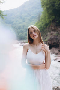 Portrait of young woman standing against river