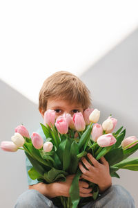 A little boy holds a tender bouquet of pink and white tulips.