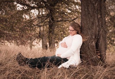 Midsection of woman sitting on tree trunk
