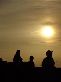 Silhouette people standing against sky during sunset