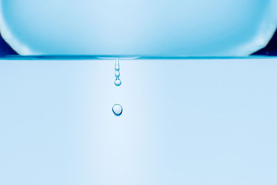 Close-up of drop falling on blue water