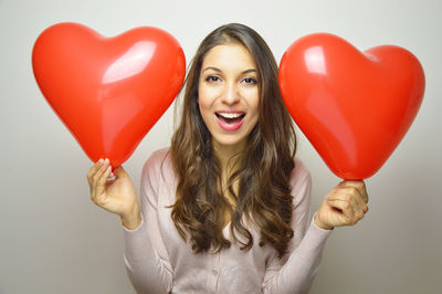 Portrait of a smiling young woman holding heart shape