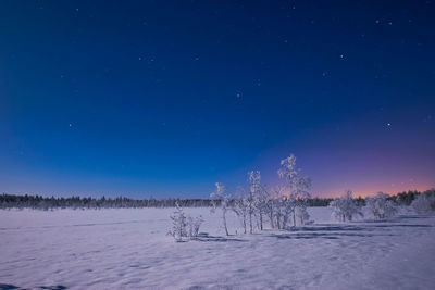 Scenic view of snowy field against clear blue sky at night