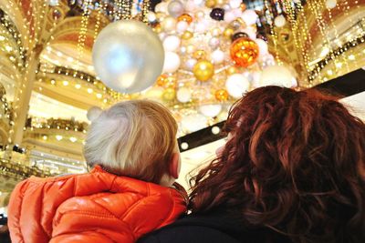 Rear view of mother and son standing against illuminated lights at night