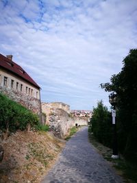 Road amidst trees and buildings against sky