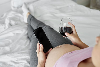 Midsection of man using mobile phone on bed