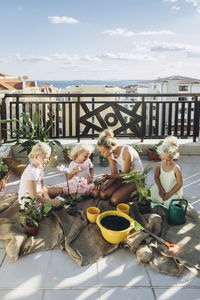 Mother and daughters planting flowers on roof terrace together