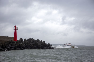 Boat navigates pass a lighthouse at tamsui fisherman's wharf in taiwan.