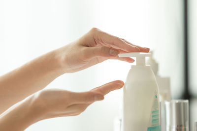 Close-up of woman hand holding bottle against blurred background