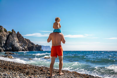 Rear view of woman standing at beach