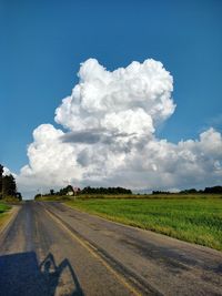 Road amidst field against sky