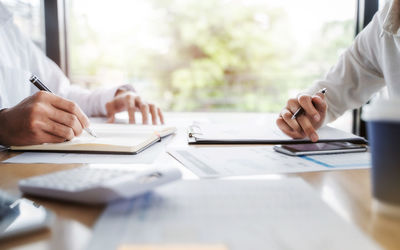Midsection of man using mobile phone while sitting on table