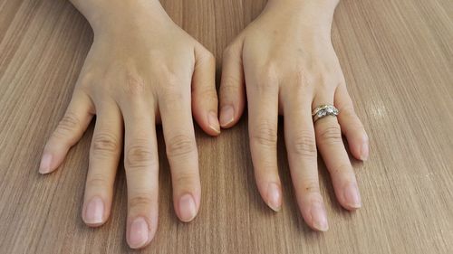 Cropped image of hands with ring on wooden table