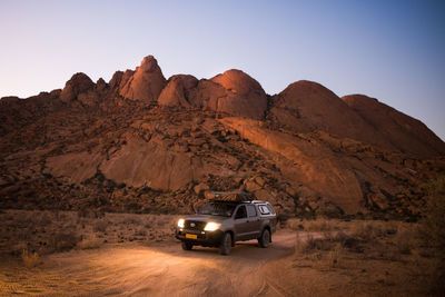 Car on desert against mountain range