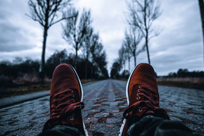 Low section of man on footpath against sky