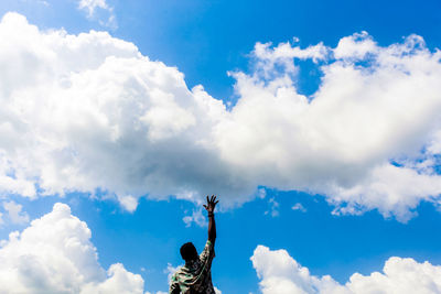 Low angle view of woman with arms raised against sky