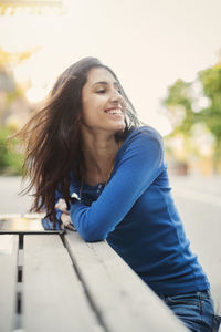 Happy teenager looking away while sitting at table outdoors