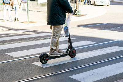 Low section of man riding electric push scooter on city street