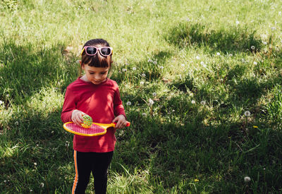 Girl holding badminton racket and ball. child exercising outside