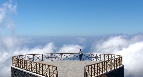 Rear view of woman standing at observation point against sky