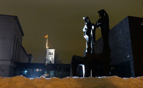 Low angle view of statue by building against sky at night