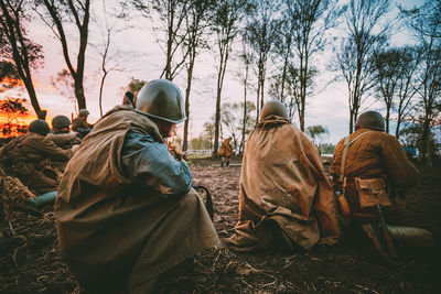 Rear view of people sitting on land against trees