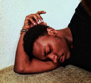 Close-up of young man sleeping on floor by wall