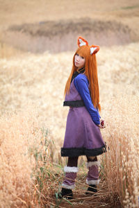 Full length portrait of woman with long hair standing on agricultural field