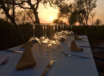 Table and trees against sky during sunset