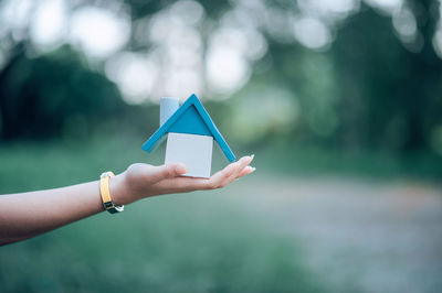 Cropped hand of woman holding model home in park