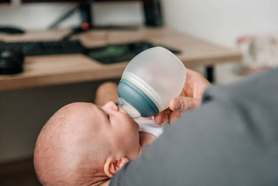 Close-up photo of dad feeding baby with bottle of baby formula