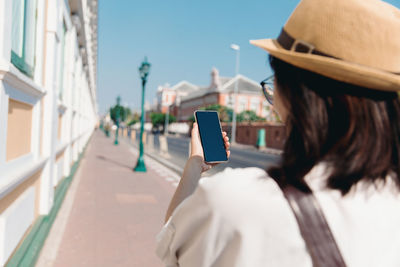 Midsection of man using mobile phone in city