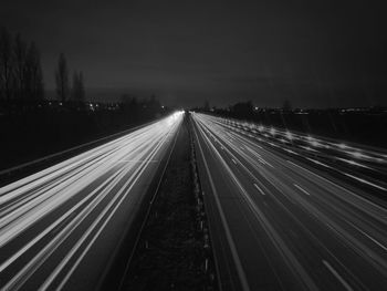 Light trails on road against sky at night