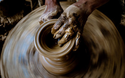 Cropped hands of man making pot in workshop