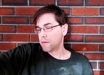 Portrait of young man wearing eyeglasses against brick wall