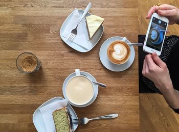 Midsection of woman photographing coffee while sitting at table