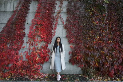 Full length portrait of woman standing against plants during autumn