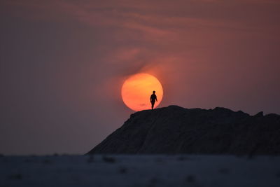 Silhouette rock on mountain against sky during sunset