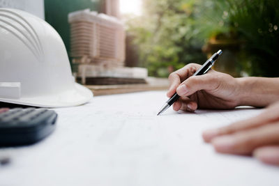 Midsection of man holding paper on table
