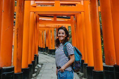 Portrait of smiling young woman standing against orange wall
