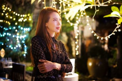 Smiling mature woman standing against illuminated lights 