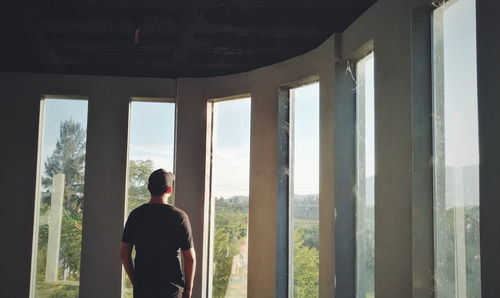 Rear view of man looking through window