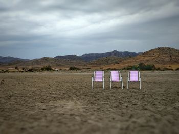 Deck chairs on beach against sky
