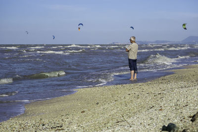 Rear view of woman on beach against sky