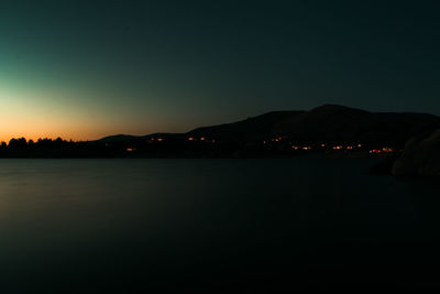 Scenic view of lake against clear sky during sunset