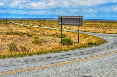 Road amidst field against sky