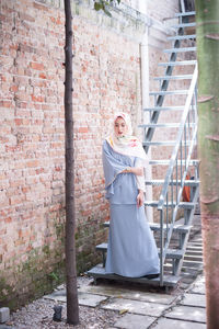 Portrait of smiling woman standing against brick wall